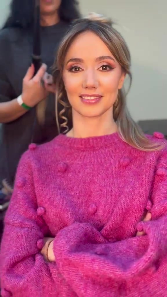 A backstage hairstyle with softly curled face-framing sections and the hair gathered behind